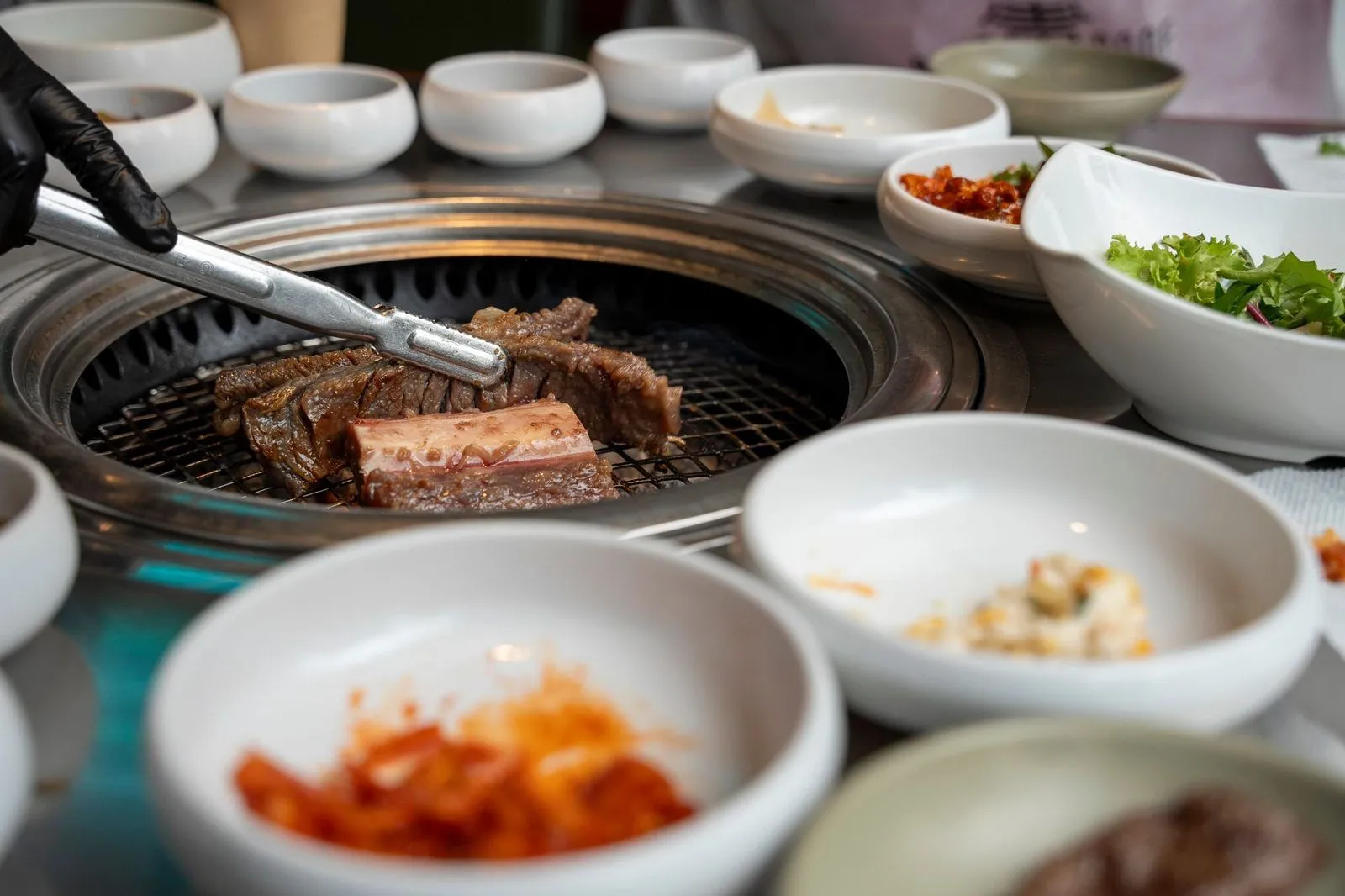 Barbacoa coreana con carne a la parrilla y bowls de banchan para acompañar el soju